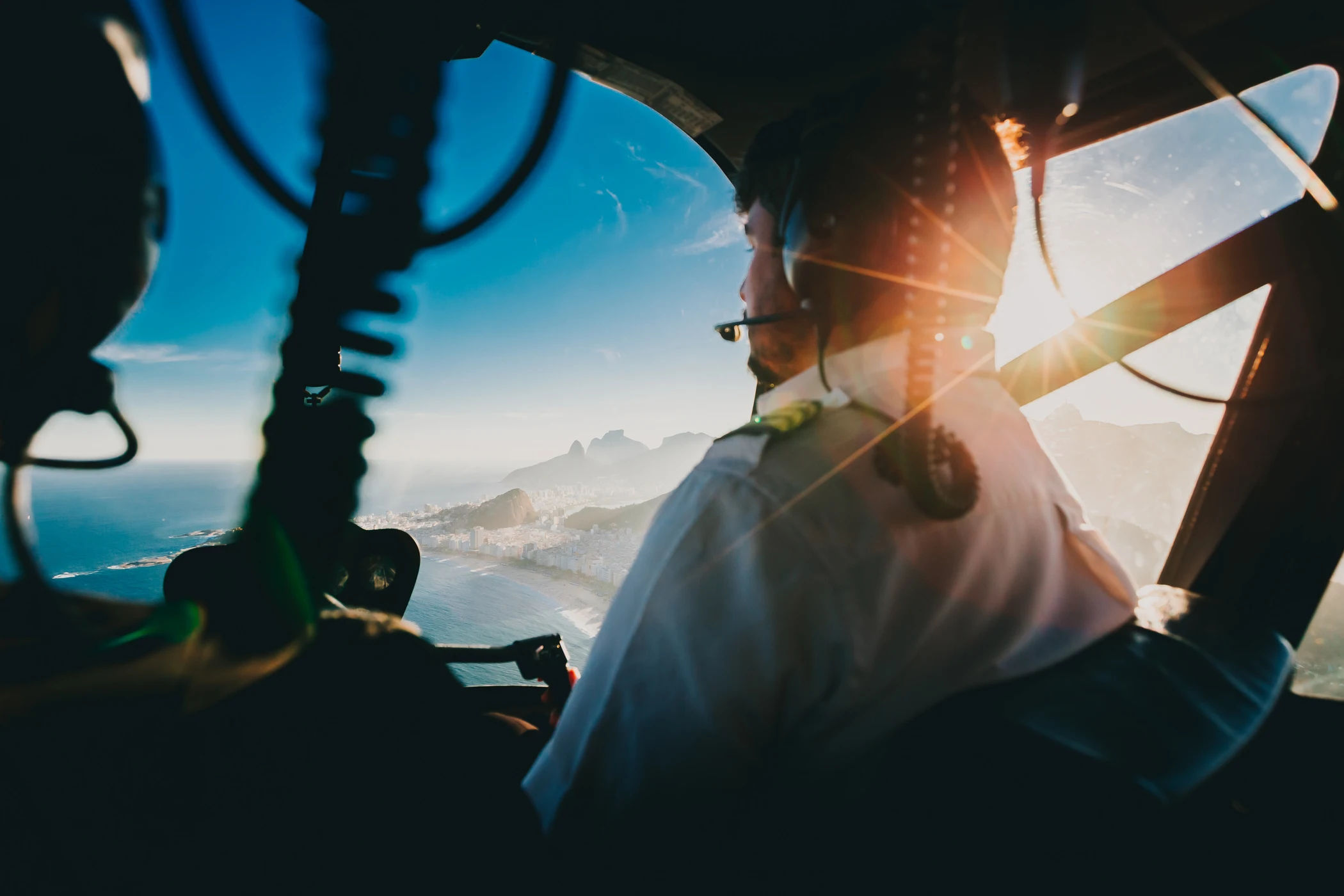Conceptual pilot in an aircraft cockpit overlooking a sunlit coastline